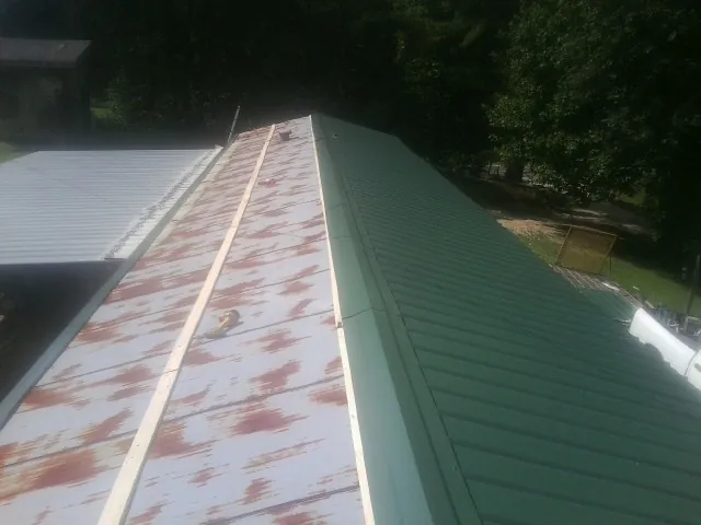 Old rusted panels beside newly installed green metal roofing — Wind Damage Roof Repair by Roofing Brothers in Lynn Haven