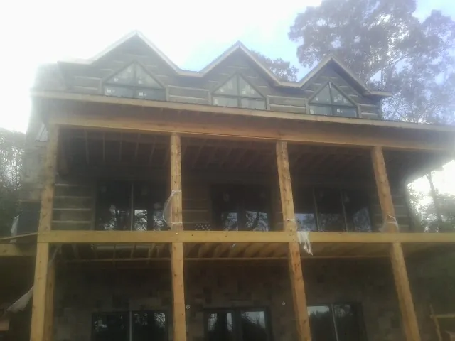 Dormers and porch framing on a large log home under construction — Roof Coating work by our crew in Lynn Haven