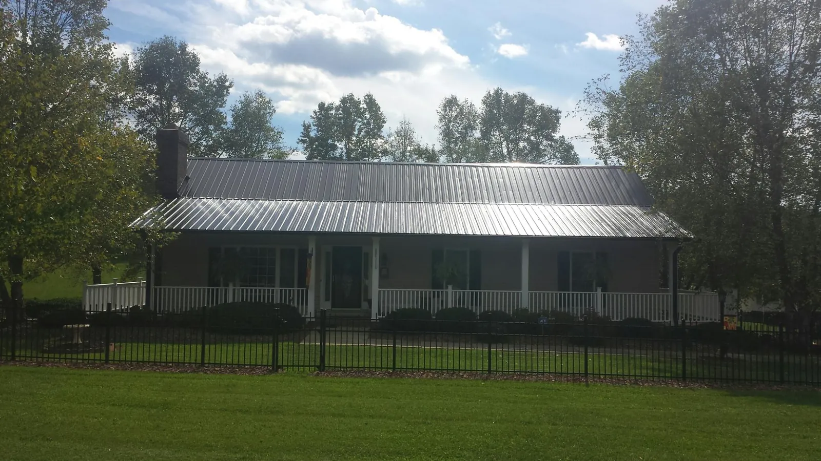 Gray metal roof on a brick ranch with a full width front porch — Gutter Guard Installation work by our crew in Lynn Haven